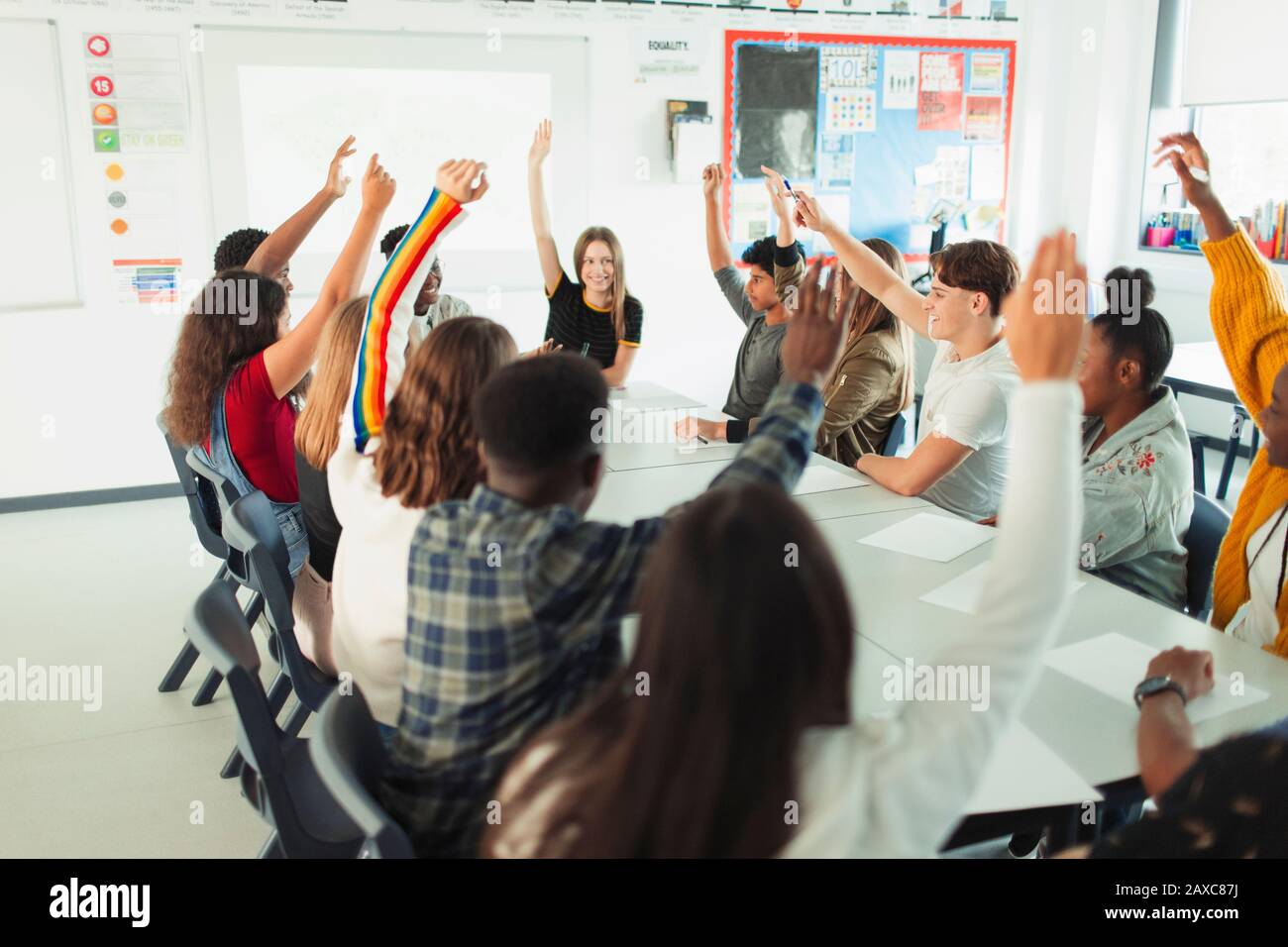High school students with hands raised in debate class Stock Photo