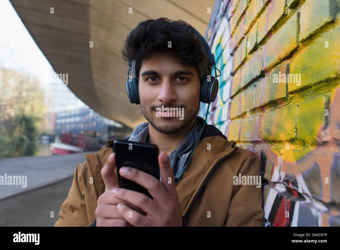 Portrait confident young man listening to music with headphones and mp3 player Stock Photo