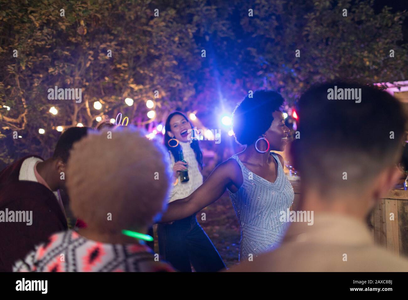 Playful friends drinking and dancing at garden party Stock Photo