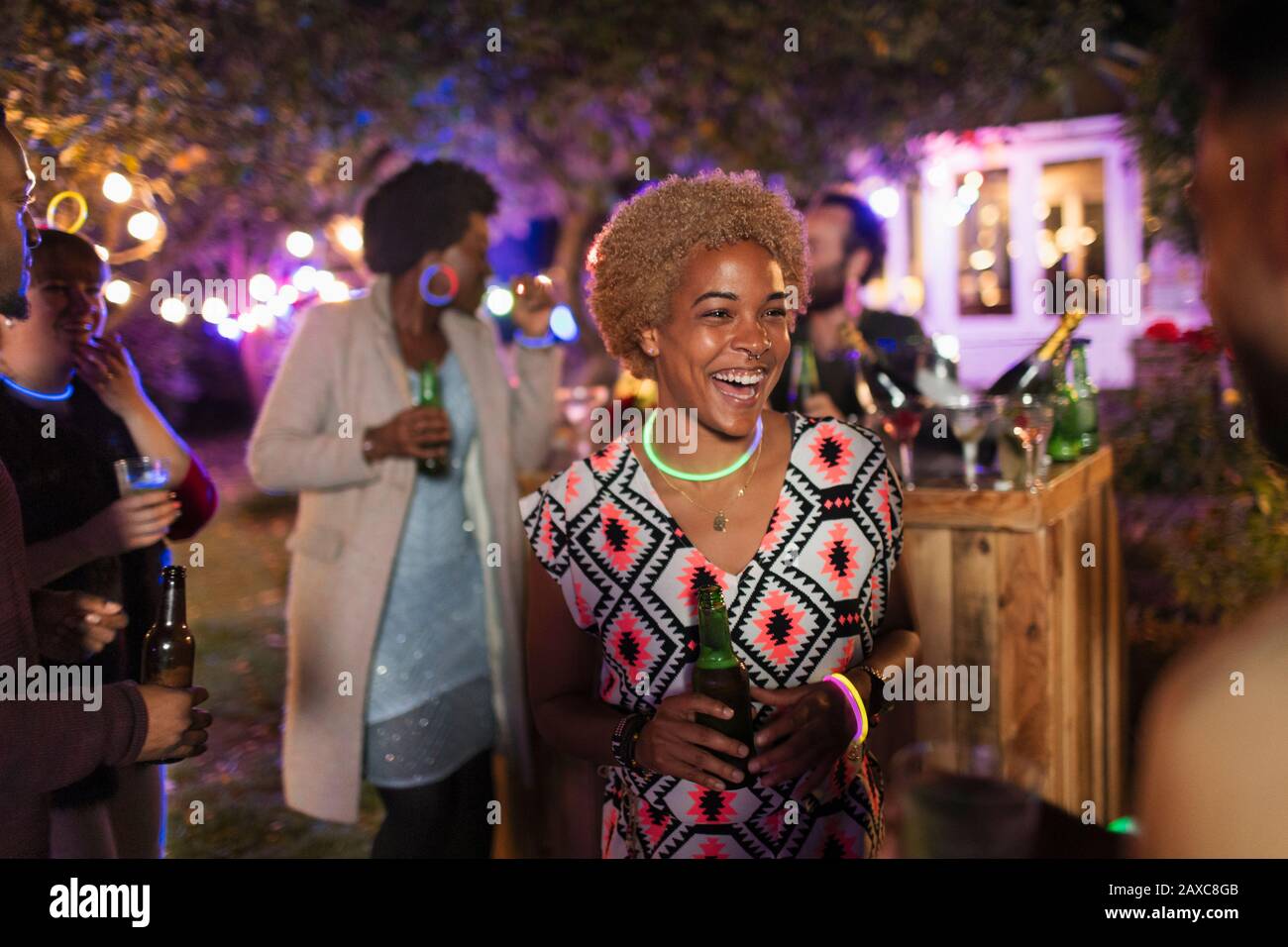 Happy woman drinking and talking with friend at garden party Stock Photo