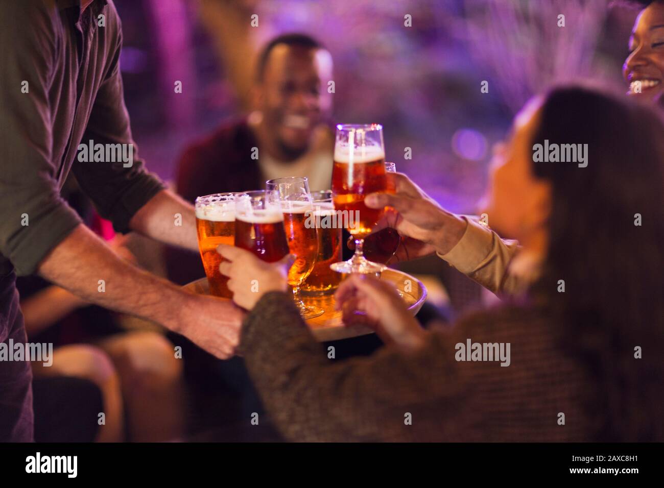 Man serving beer glasses to friends at party Stock Photo