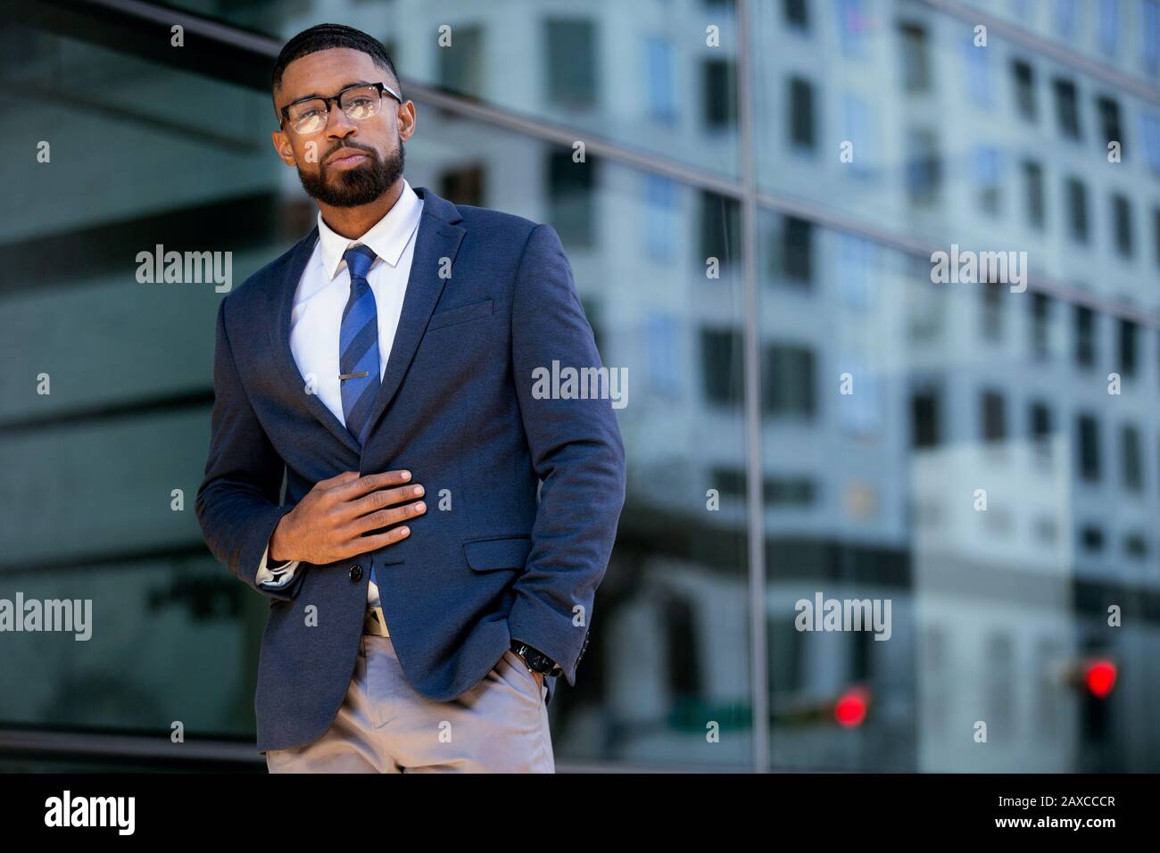 Proud successful businessman executive CEO african american, standing confidently with arms folded in downtown, financial buildings and skyscrapers Stock Photo