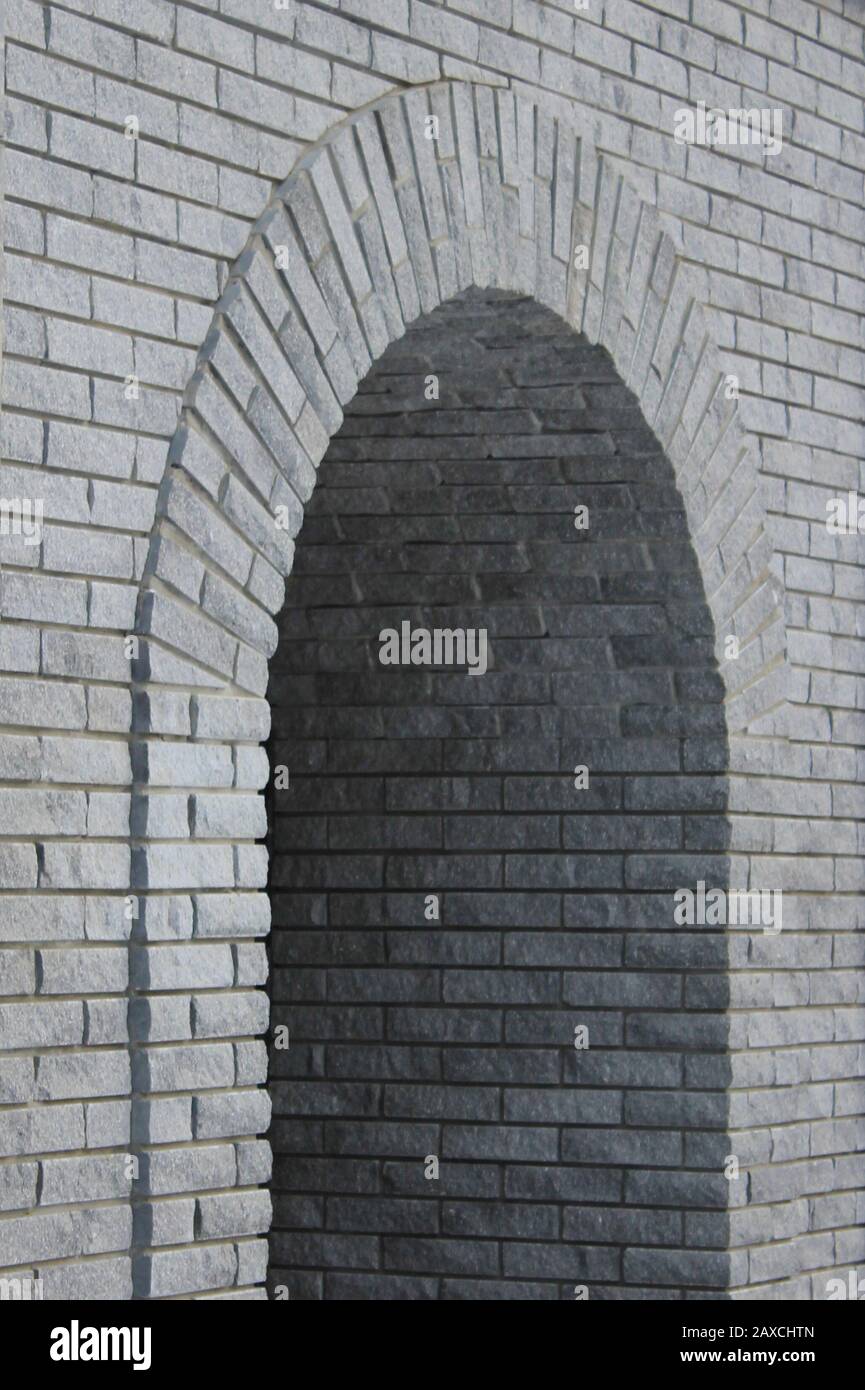 Brick gray wall with a semicircular arch entrance. Rough cement texture. Stock photo for web, print, background and wallpaper with empty space for text. Stock Photo