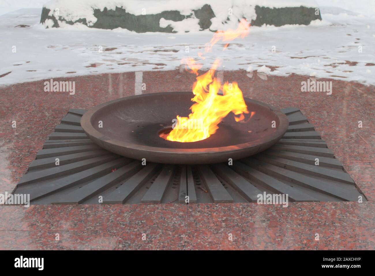 Burning flame bright orange color on snow background. Granite memorial flame in a flat bowl. Stock photo for web and print. Stock Photo