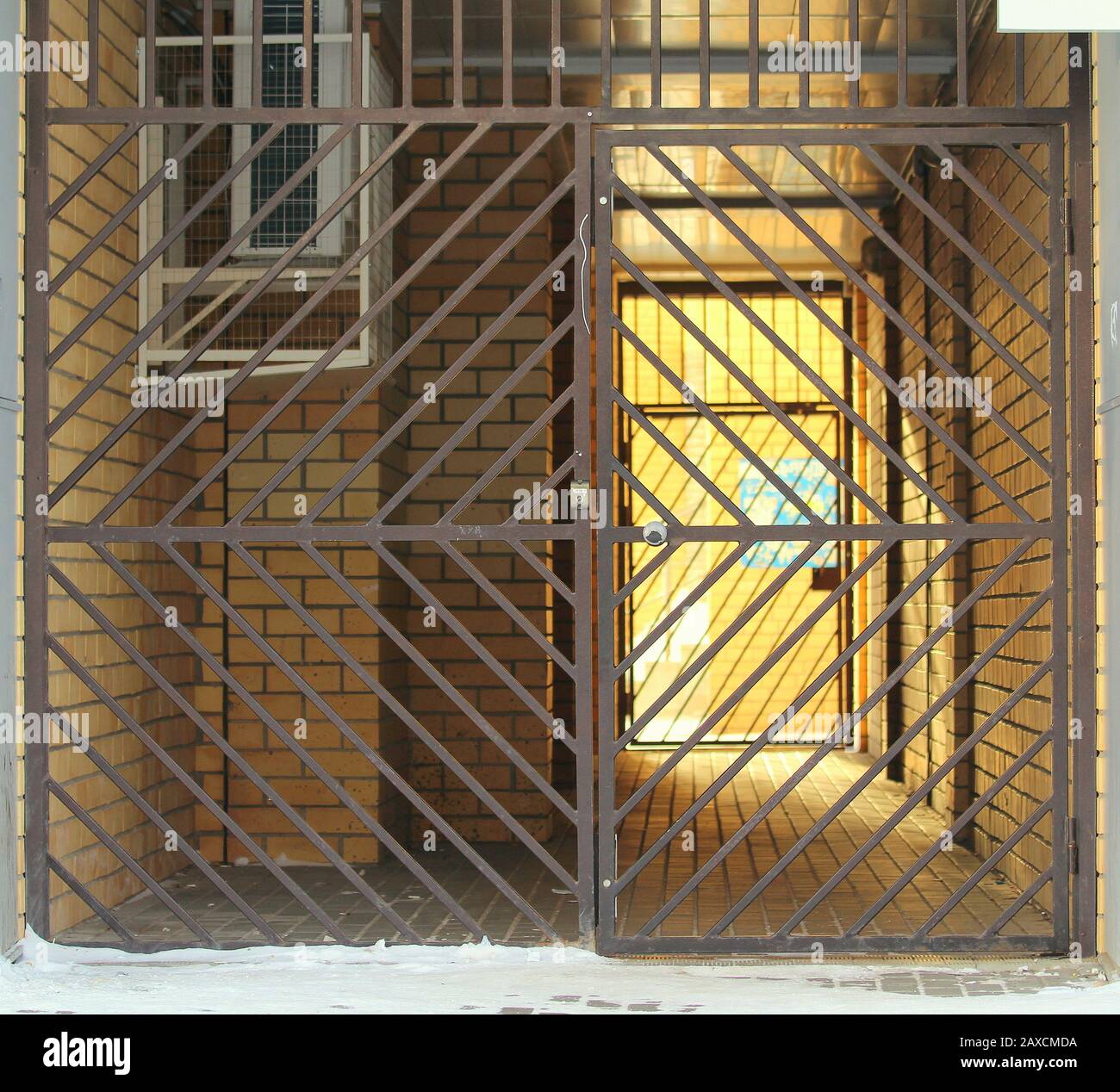 Metal gates blocking the courtyard. Brick walls lit by bright sunlight