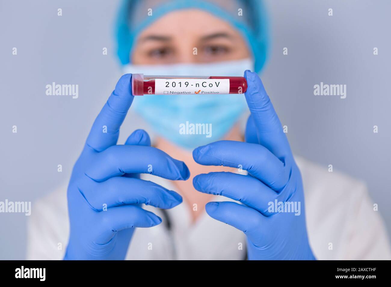 Nurse holding test tube with Positive Coronavirus test blood sample. Virus test and research concept. Focus is on blood test tube. Stock Photo