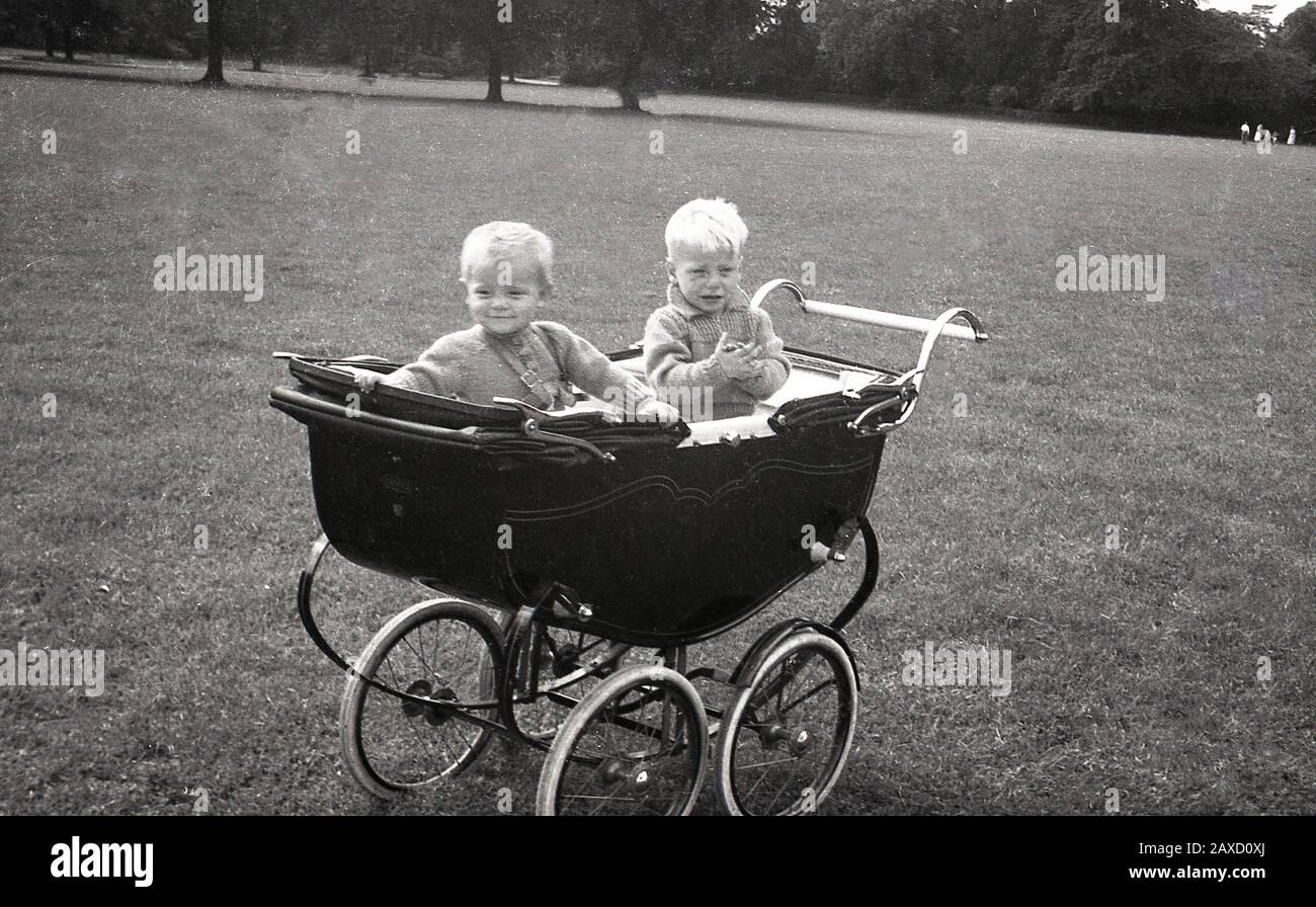 1940s, historical, two infant boys sitting in a luxury Briitsh made 'Harris' coach-built baby carriage sat in a park, England, UK. Founded in 1870 in the Old Kent Rd, London, by William James Harris as a reseller of sewing machines - Harris had worked for the Singer Sewing Company for several years - in 1880 Harris decided to begin make his own prams, which became their main business activity. The company was brought by Mothercare in the 1960s. Stock Photo