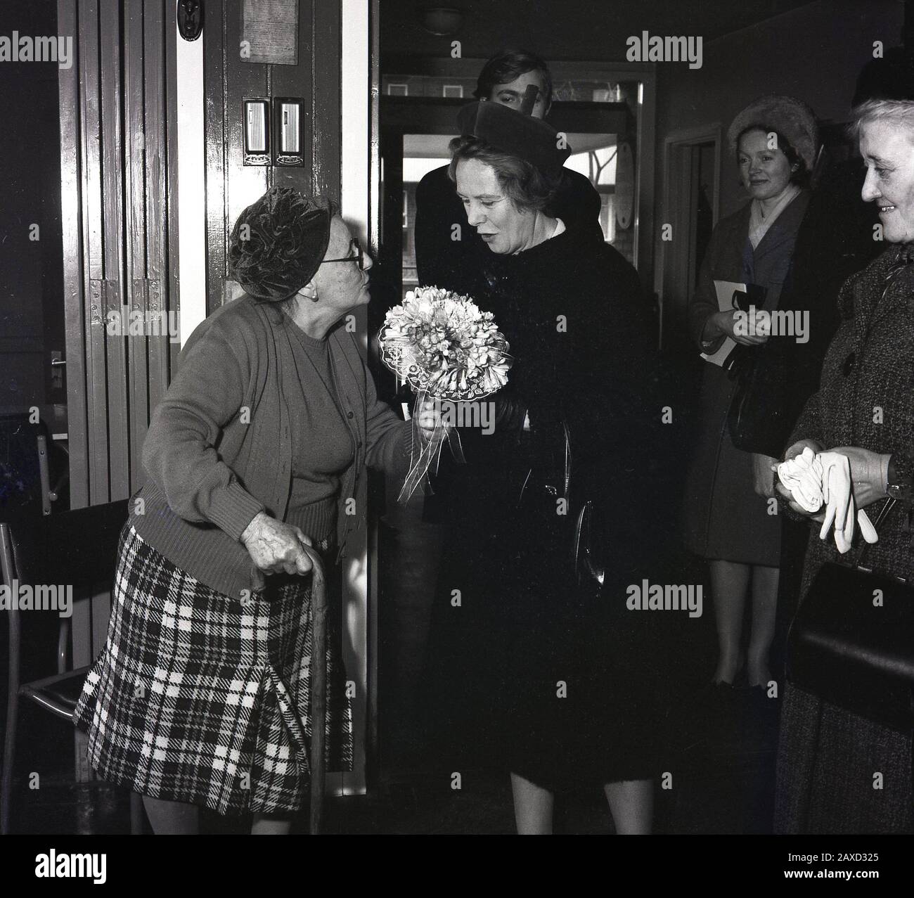 1960s, historical, Mrs Wison, the wife of the British Prime Minster, Harold Wilson, receiving a bunch of flowers from a female resident of an old peoples home, on visit there, South London, England, UK. The spouse of British prime ministers do not have official roles or duties, but have often undertaken charitable work and visits to those on the margin of society. The daughter of a congregationalist minister, Mary Wilson was an unassuming woman who wrote poetry and enjoyed family life and became  the first spouse of a British prime minister to live beyond 100, at 102 years. Stock Photo