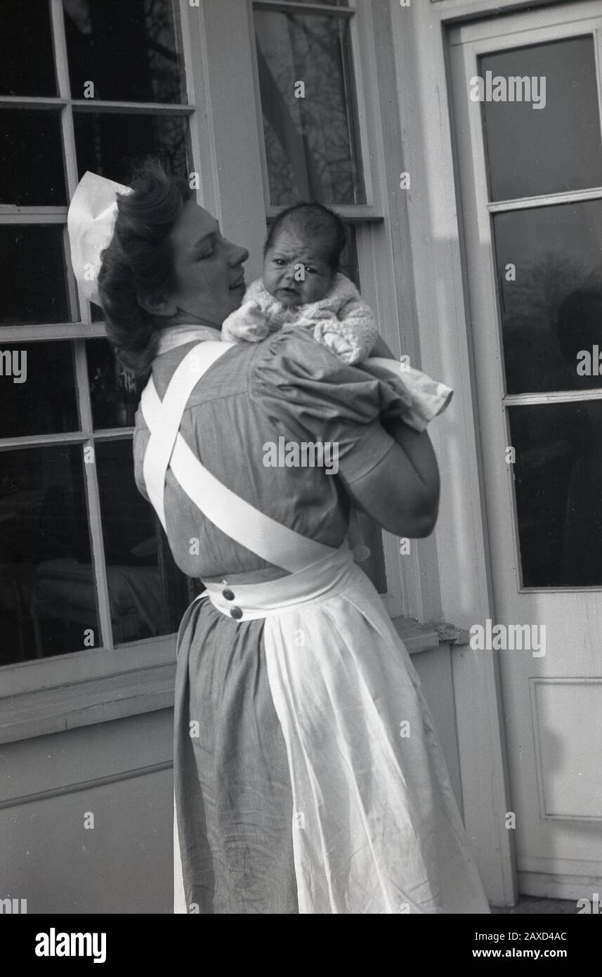 1940s, historical, outside, a uniformed maternity nurse holding a baby, England, UK. Stock Photo