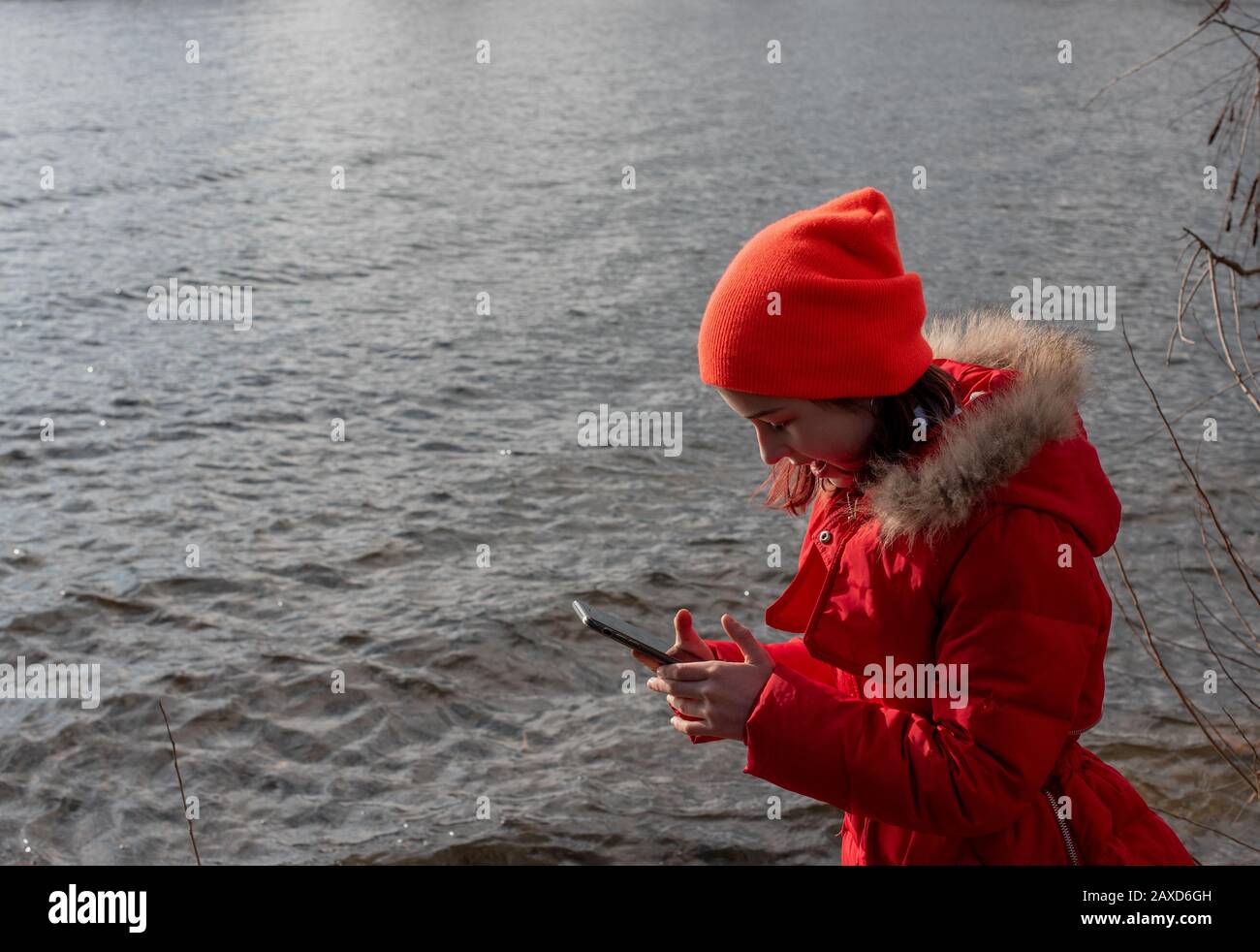 Girl dressed in red jacket, poses for making selfie or photo of herself