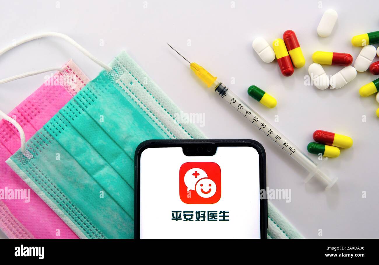 Ping An Good Doctor logo seen on the smartphone which placed on top of viral masks, syringe and pills. PAGD provides real-time medical consultation. Stock Photo