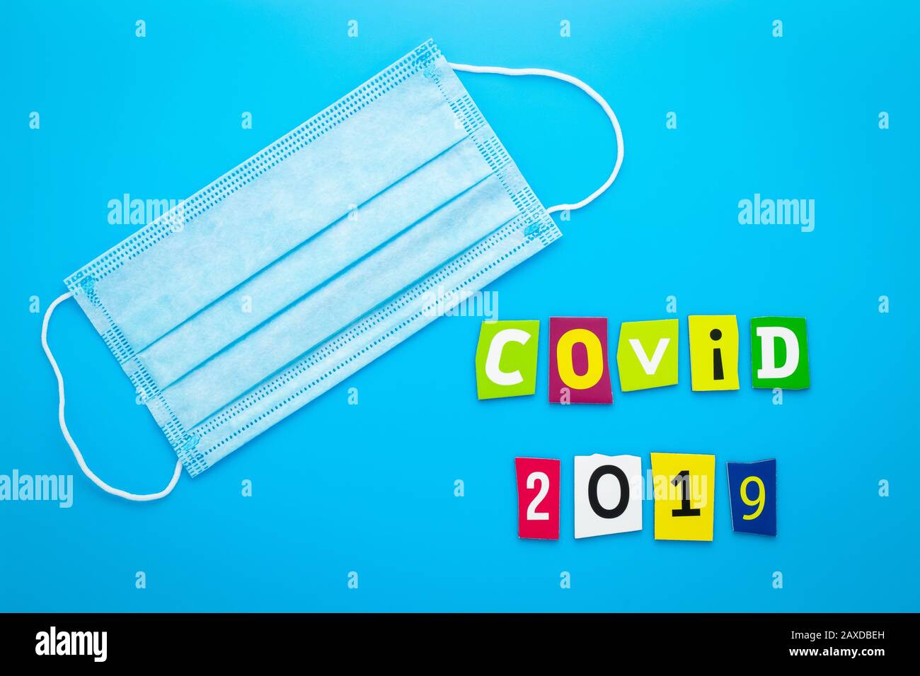 Text Covid-2019. Coronavirus. Medical masks on blue background. Respiratory mask for protection from viruses. Heading, banner Stock Photo
