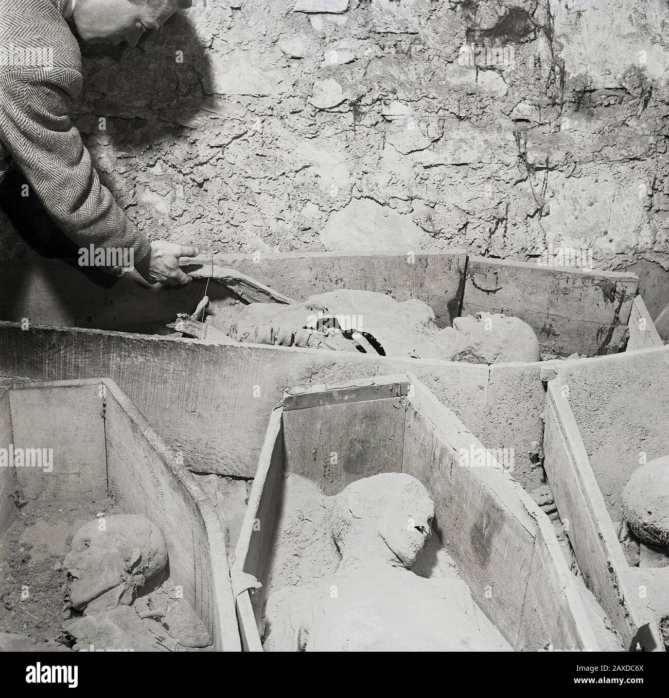 1950s, historical, burial site....a man looking at old dead bodies in open wooden coffins, Ireland. Stock Photo