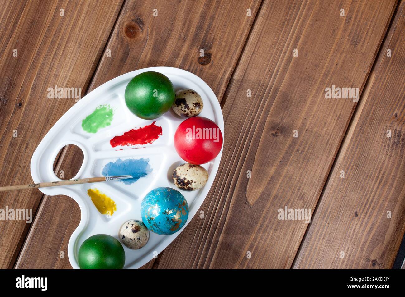 Colored eggs and paint on a wooden table, Easter background Stock Photo