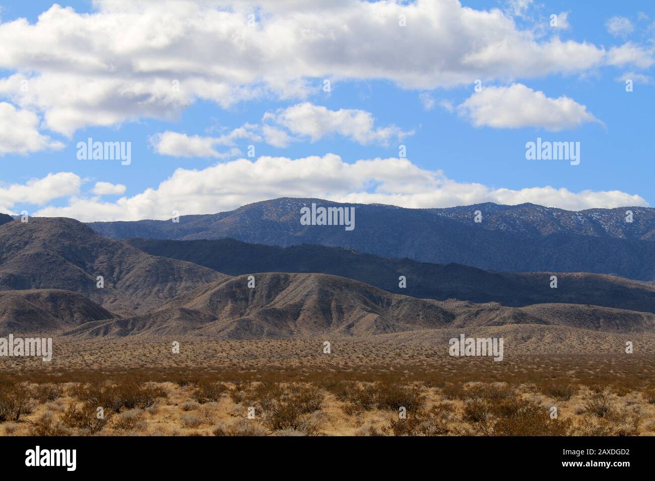 a blue cloudy sky with shadows on distant desert mountains Stock Photo ...