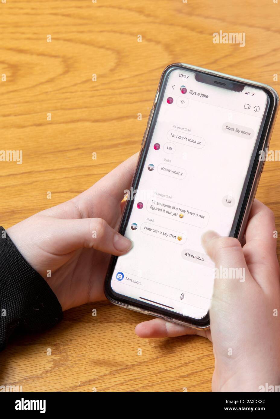 teenage girl being a cyber bully or being abused  on social media text on phone , hand level  copy space above Stock Photo