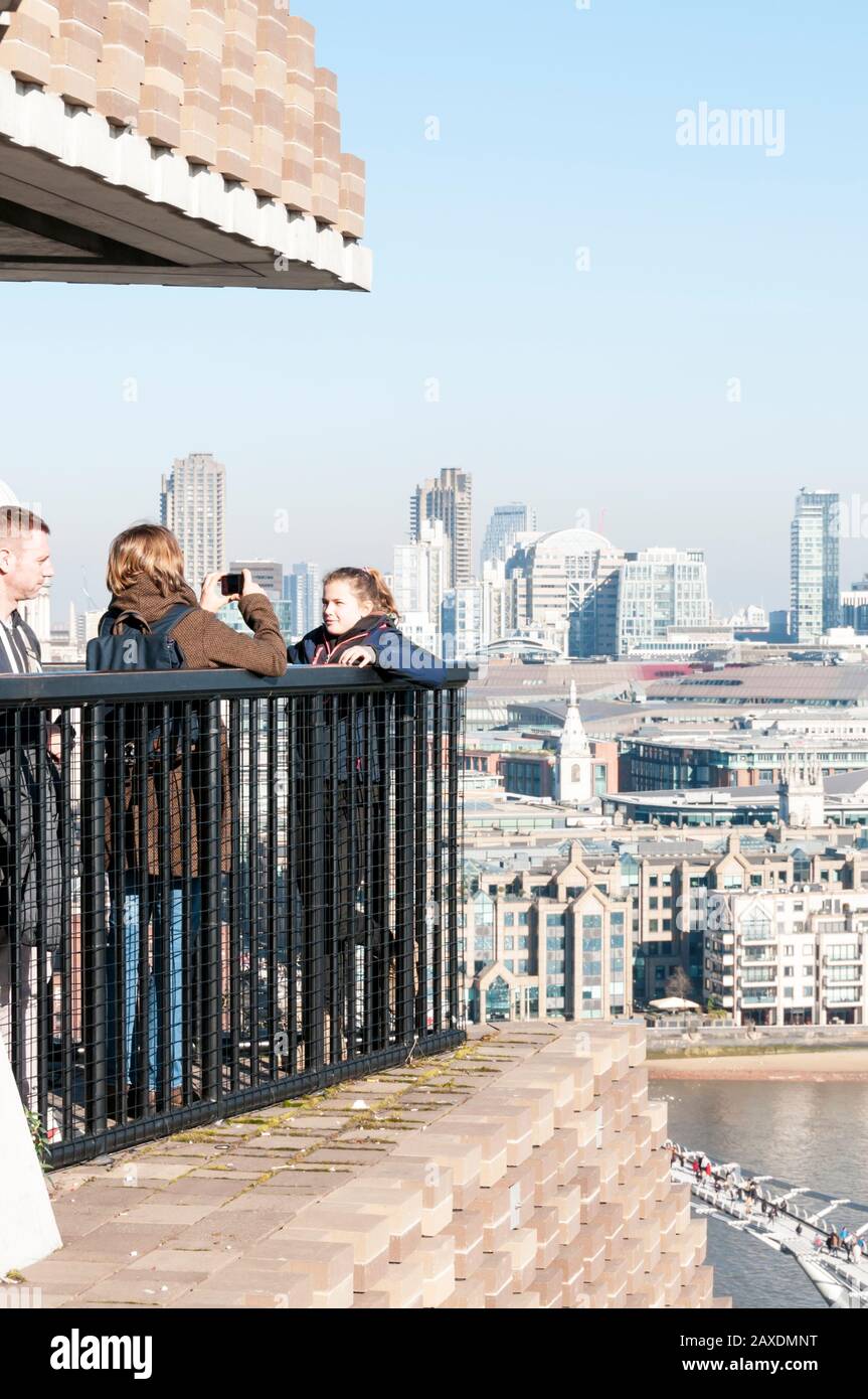 Tourists taking photographs of themselve in front of the view of London from the viewing level of the Blavatnik Building at Tate modern. Stock Photo