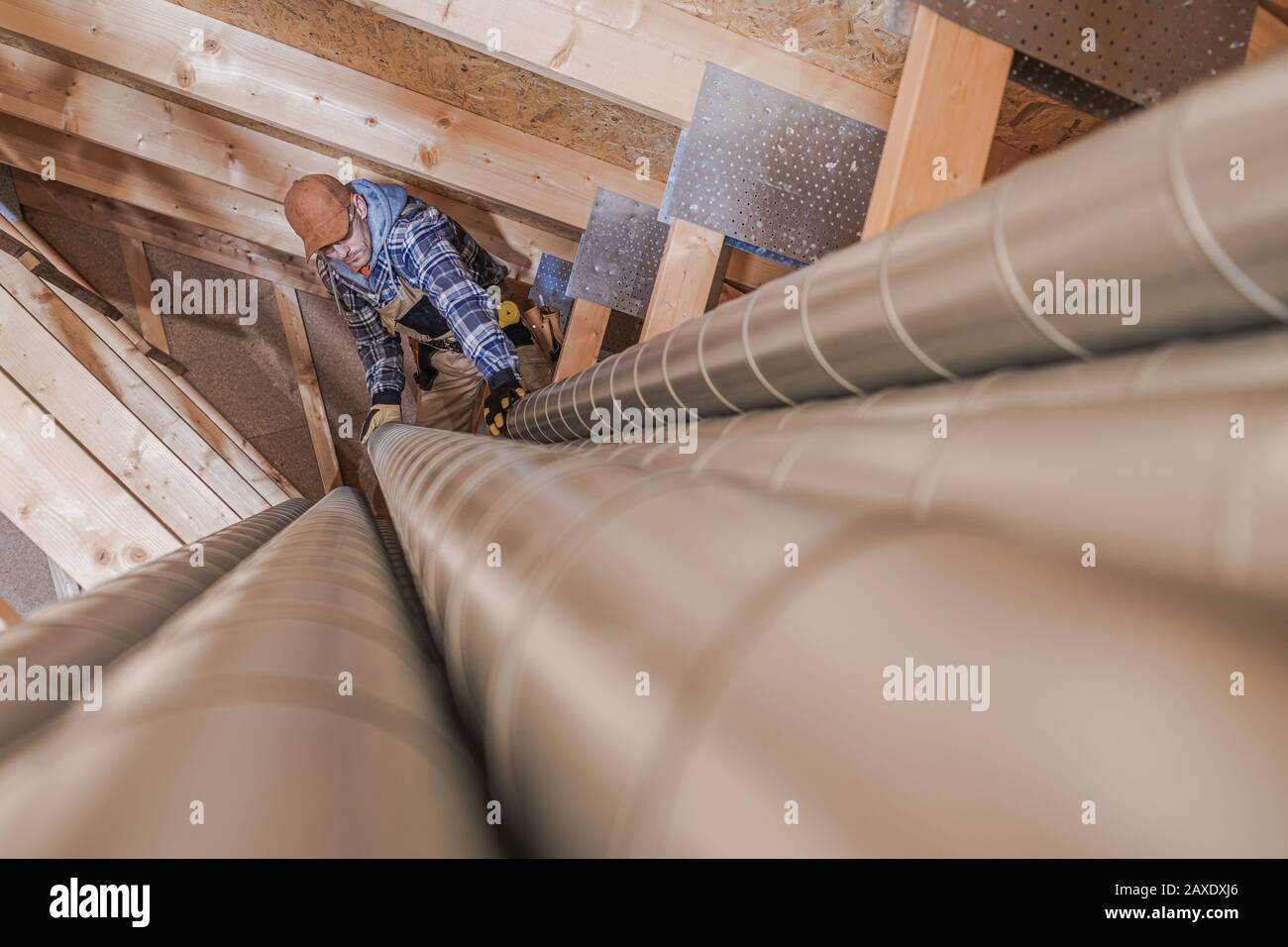 Residential Air Ventilation Pipeline Building. Worker Preparing Metal Air Vent Pipes. Stock Photo