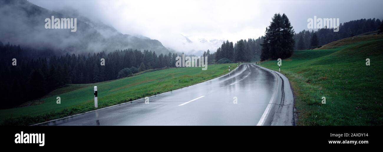 Wet highway passing through a forest, Austria Stock Photo
