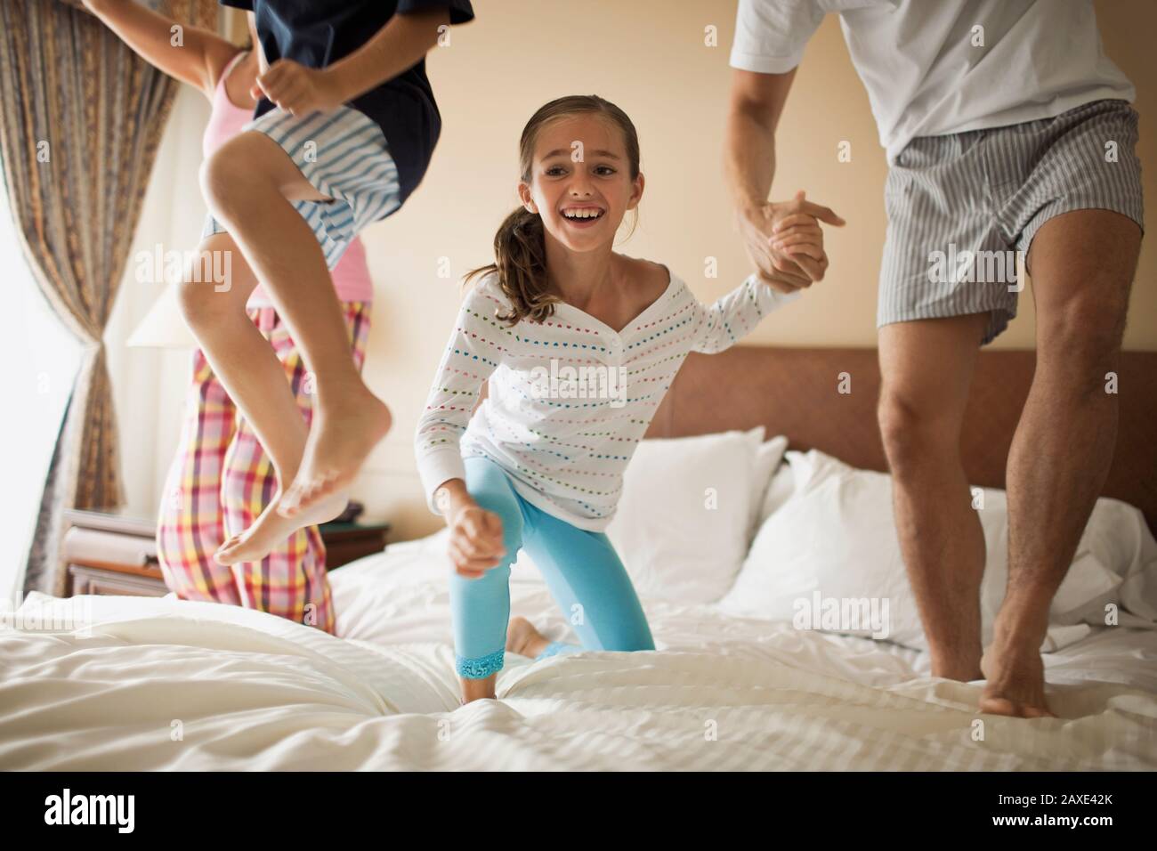 Family jumping on bed together Stock Photo