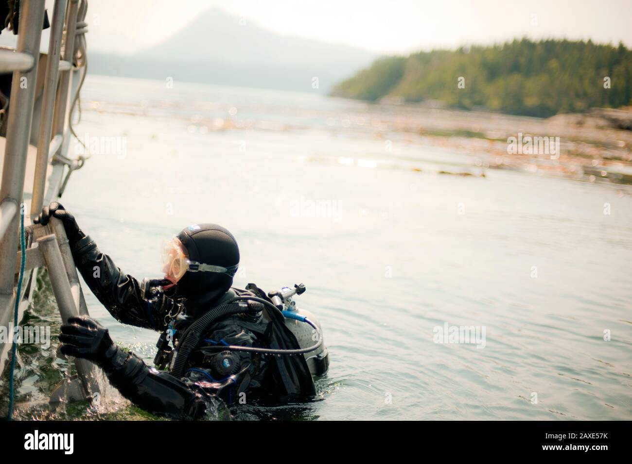 Scuba diver climbing out of the water and onto a boat Stock Photo