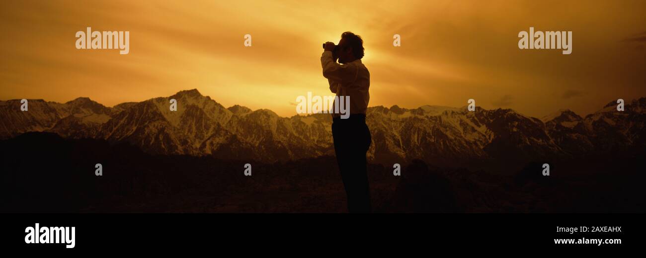 Silhouette of a man looking through binoculars, Californian Sierra Nevada, California, USA Stock Photo