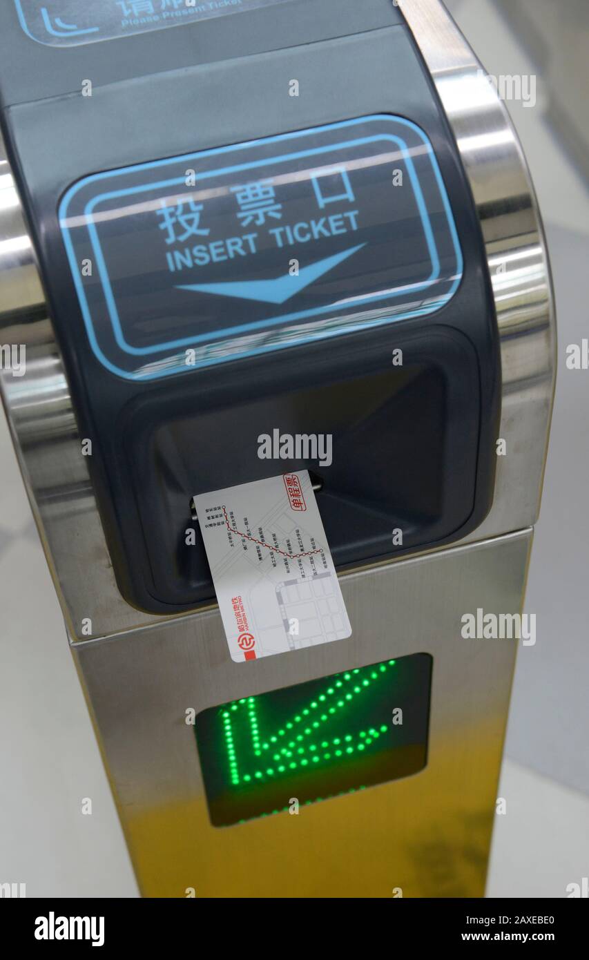 A single-journey ticket is inserted into the ticket barrier at a station on the metro system in Harbin, China Stock Photo