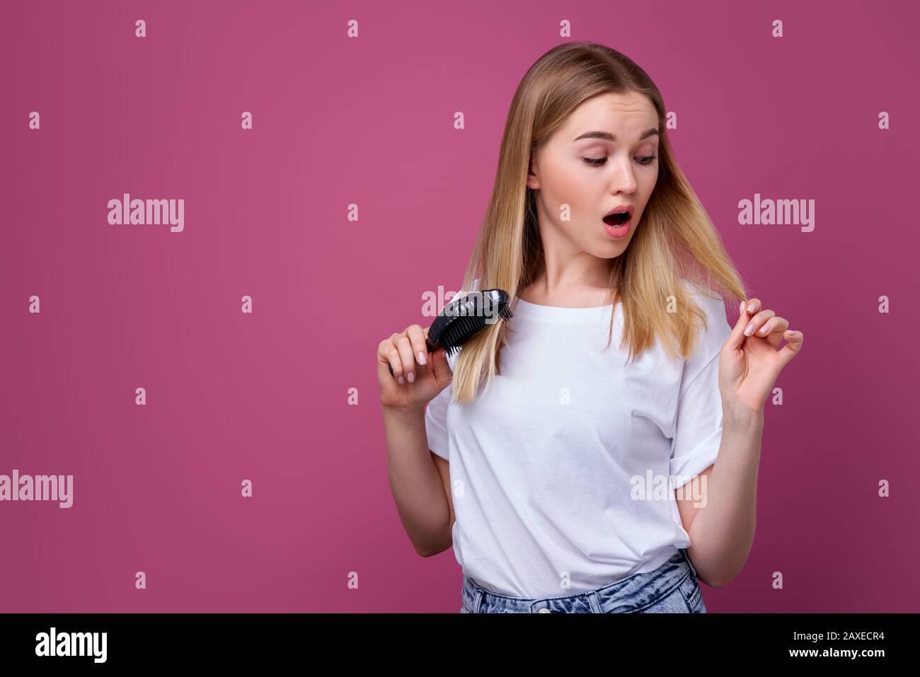 Beautiful woman is looking shocked at her hairbrush, blonde hair, young woman, Stock Photo