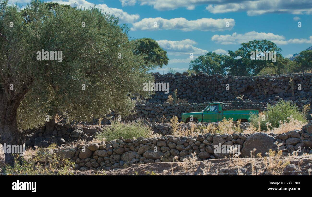 Abandoned green pickup truck in a field with stone walls on the island of Lesvos in Greece Stock Photo