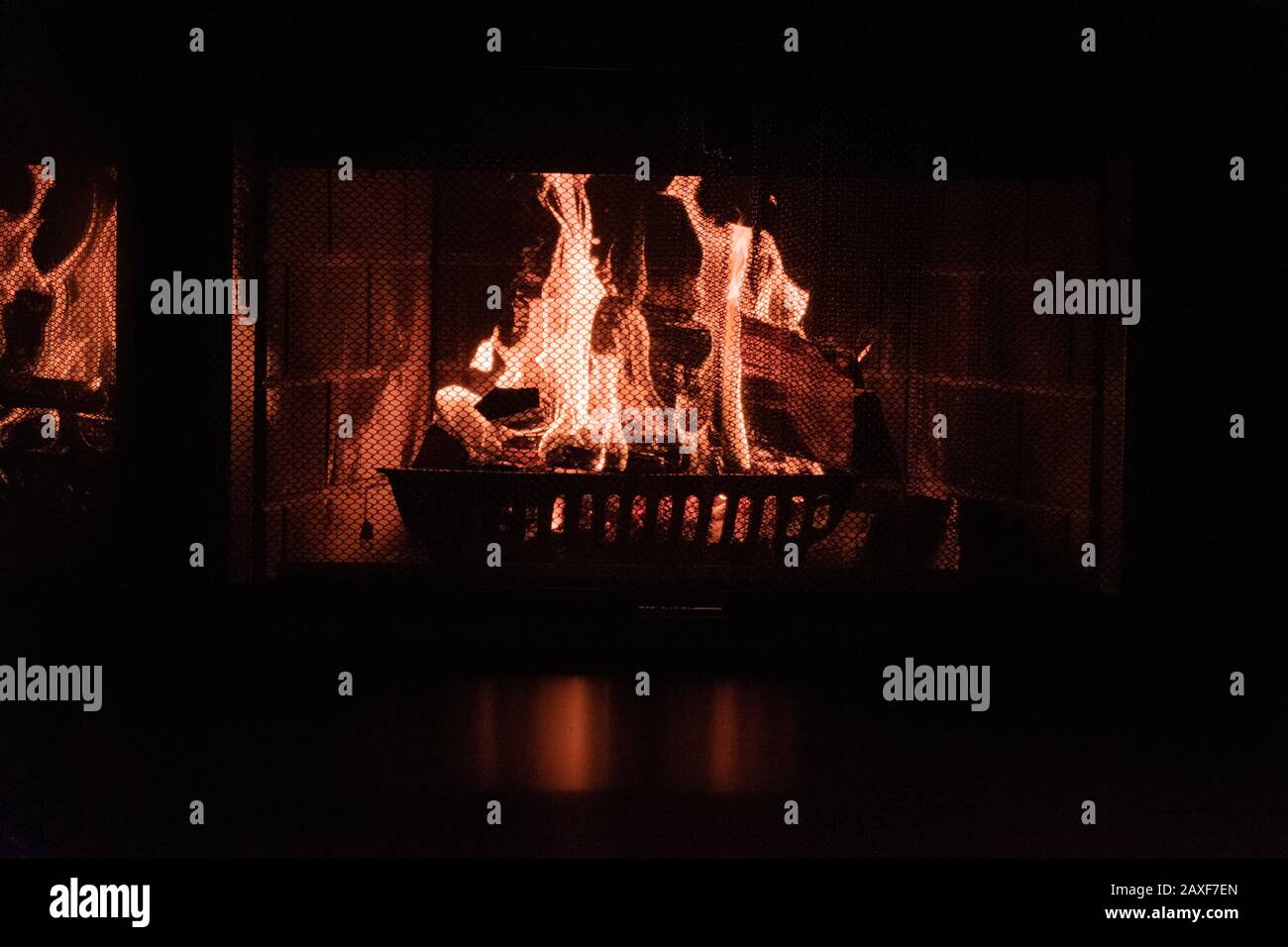 Closeup shot of a fire in a brick fireplace with screen Stock Photo