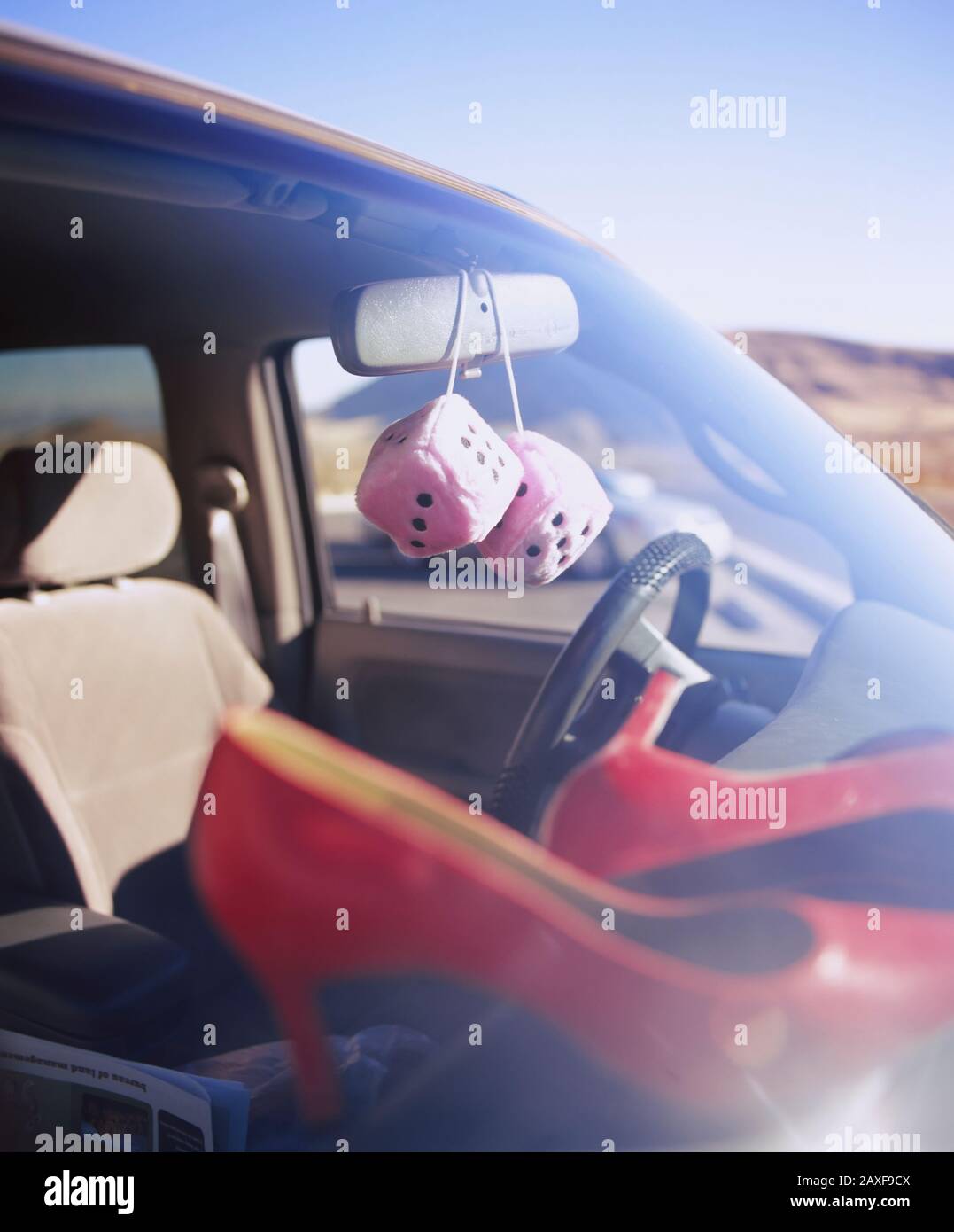 Closeup of a pair of high heel shoes on the dashboard with fuzzy dices