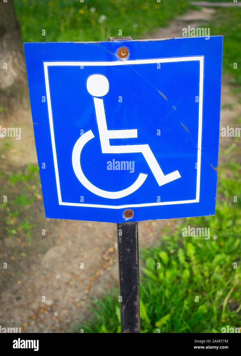 Vertical picture of a blue road sign for disabled people surrounded by ...