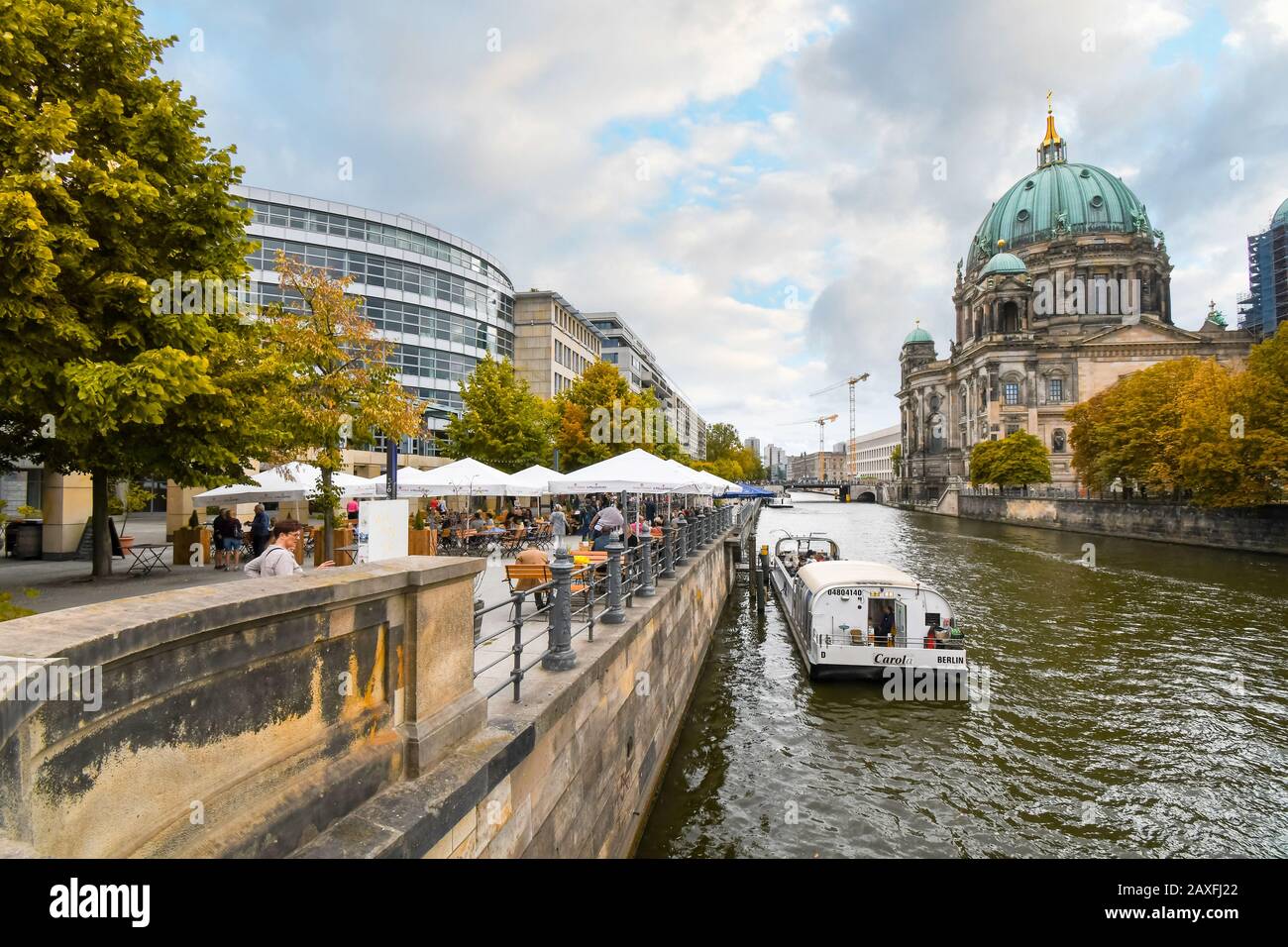 Tourists enjoy an autumn afternoon at a waterfront cafe along the Spree River with the Berlin Cathedral in view. Stock Photo