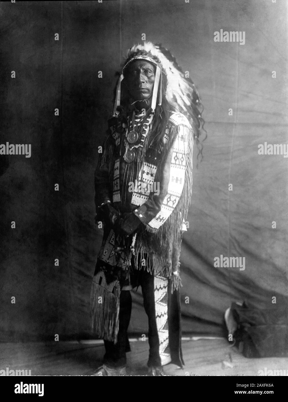 1907, USA :  Native American CHIEF  Jack Red Cloud of Oglala Lakota ( Sioux ) ( 1822 –  1909 ) . Photo by Edward S. CURTIS ( 1868 - 1952 ). - CAPO NUVOLA ROSSA - The North American Indian - HISTORY - foto storiche - warbonnet  - foto storica  -  Indians - INDIANI D' AMERICA - PELLEROSSA - natives americans  - Indians of North America - CAPO TRIBU' INDIANO - GUERRIERO - WARRIOR - portrait - ritratto  - SELVAGGIO WEST - piuma - piume - feathers  - STOCK - necklace - collana - fringes - frangia - frangie  © Archivio GBB / Stock Photo