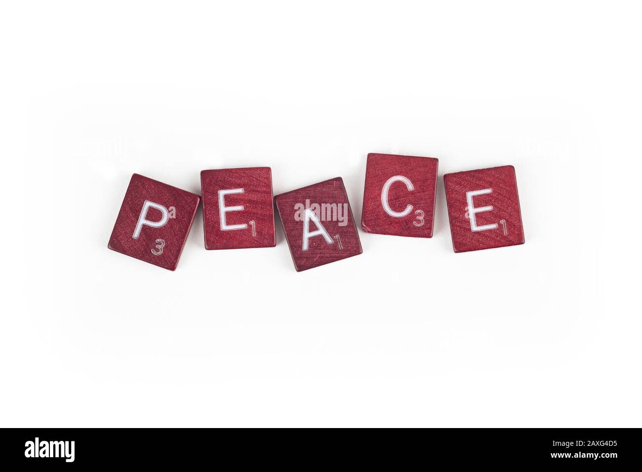 The word peace spelled out in an uneven arrangement of game letter tiles. Stock Photo
