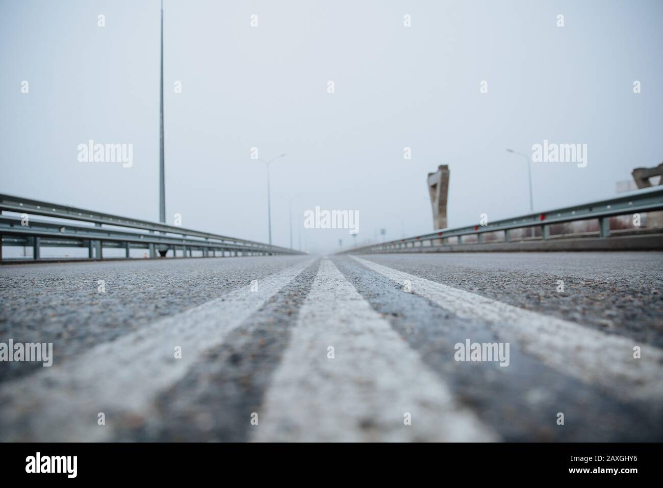 The dividing line on the road is white the view from below on the road paved going. Road markings on asphalt on the street. Stock Photo