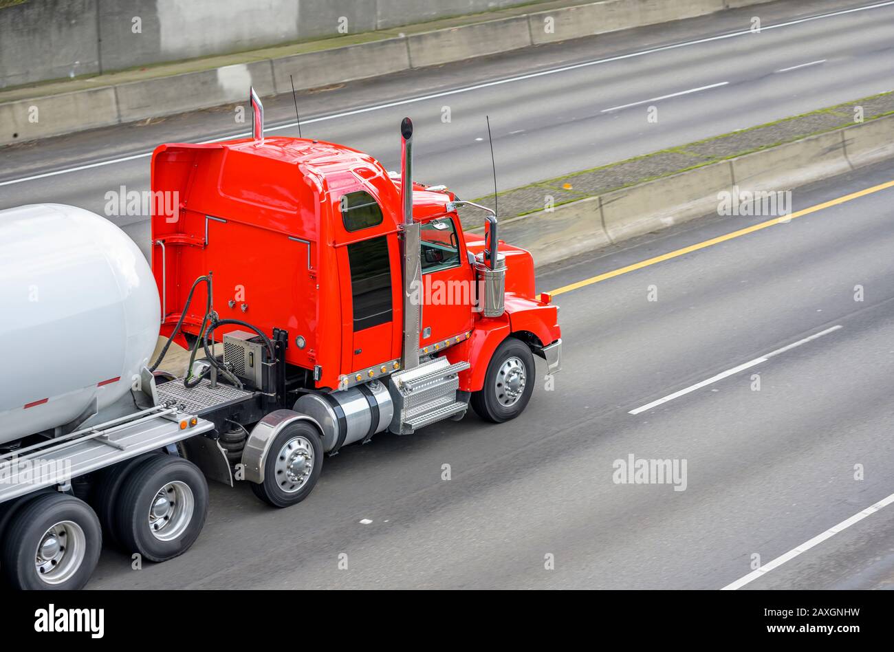 Big rig powerful diesel industrial red semi truck transporting tank
