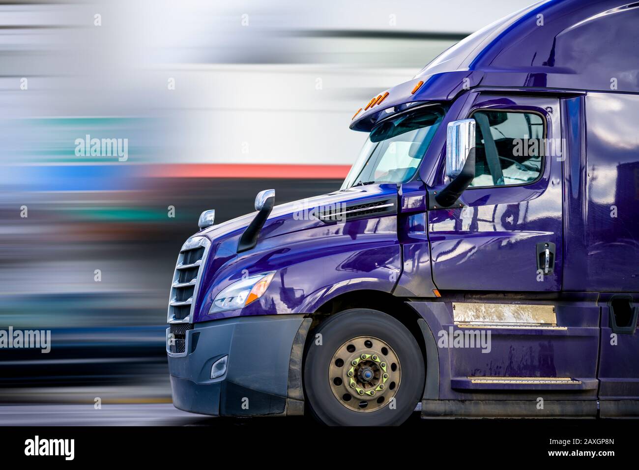 Bright Purple Bonnet Big rig long haul diesel Semi Truck with high cab configuration for improve aerodynamics transporting Commercial Cargo Driving on Stock Photo