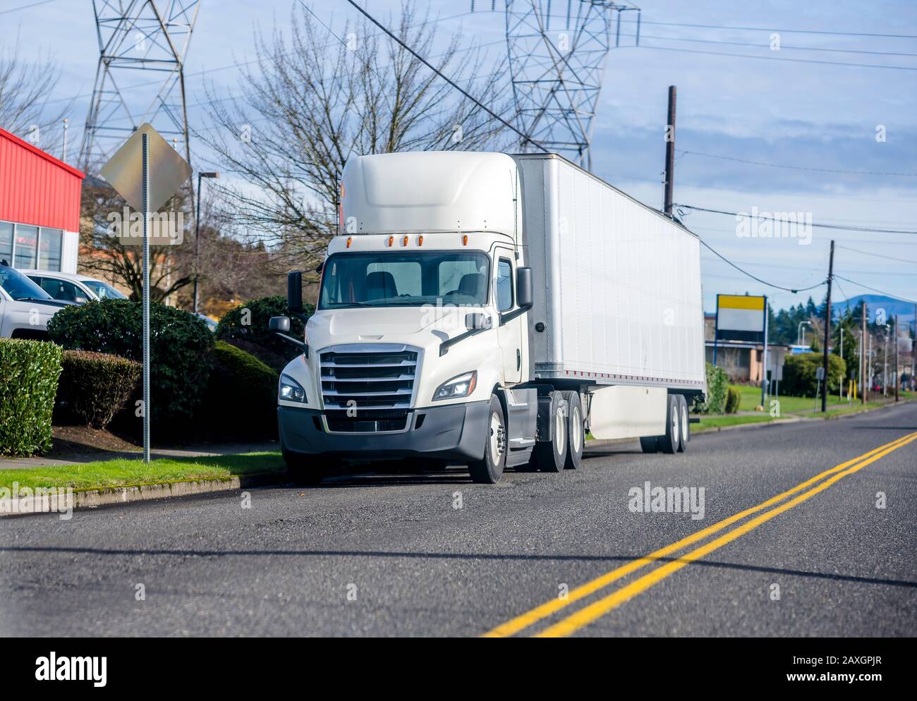 Bright White Bonnet Big rig long haul diesel Semi Truck with day cab and spoiler configuration for improve aerodynamics transporting Commercial Cargo Stock Photo