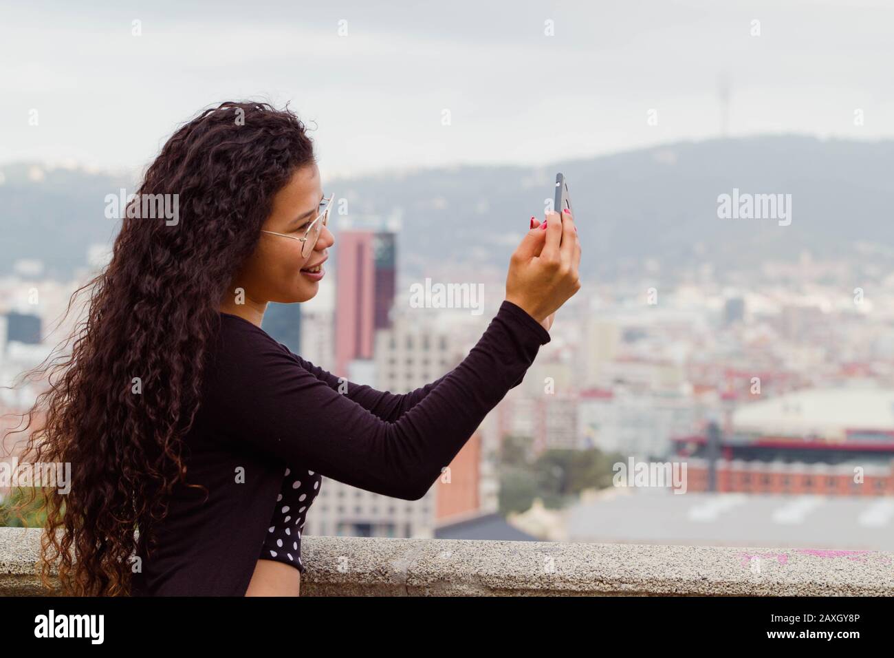 Attractive woman tourist taking a selfie, cityscape on the background Stock Photo