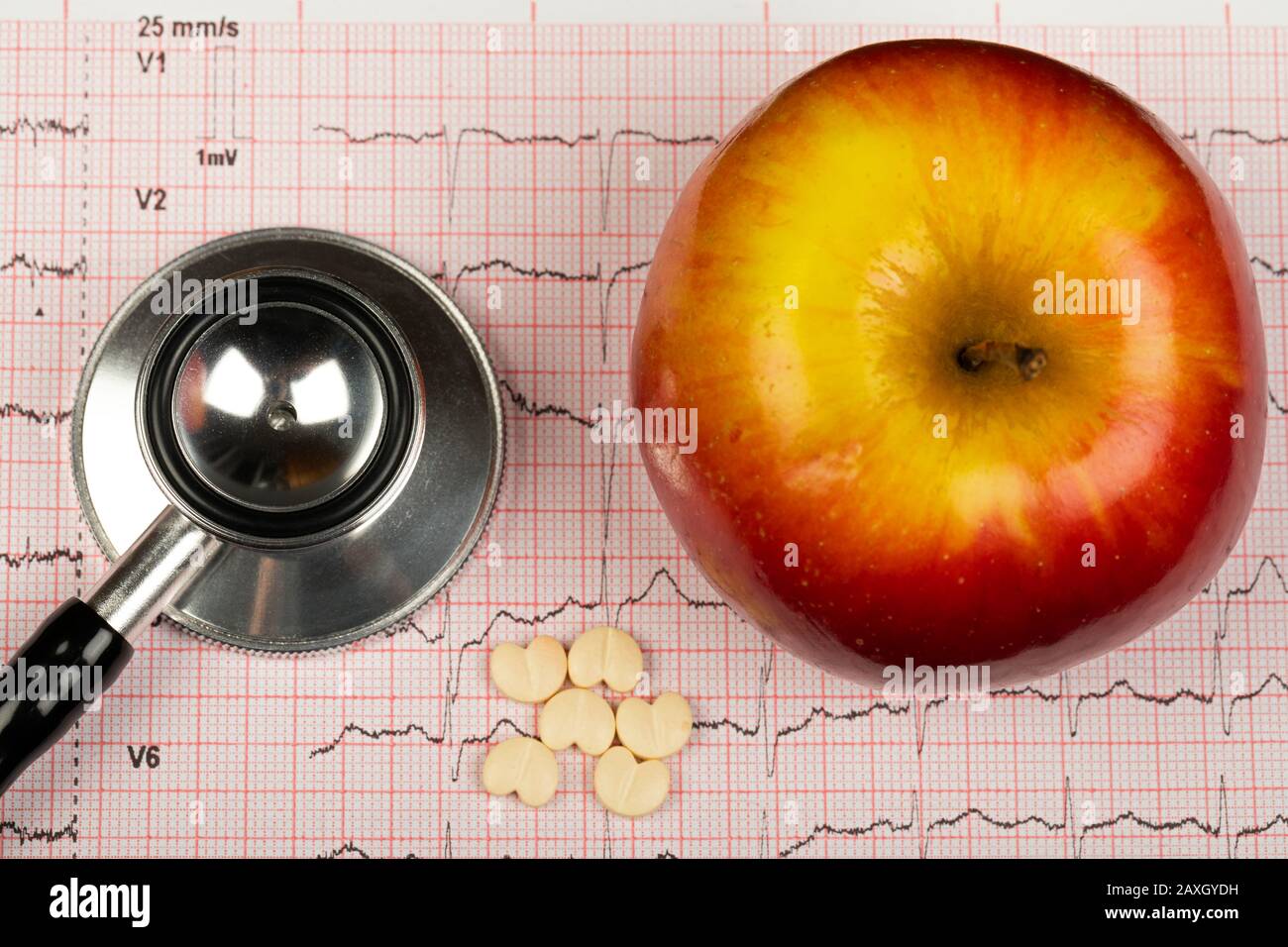 Electrocardiogram graph report with stethoscope and apple on it Stock Photo