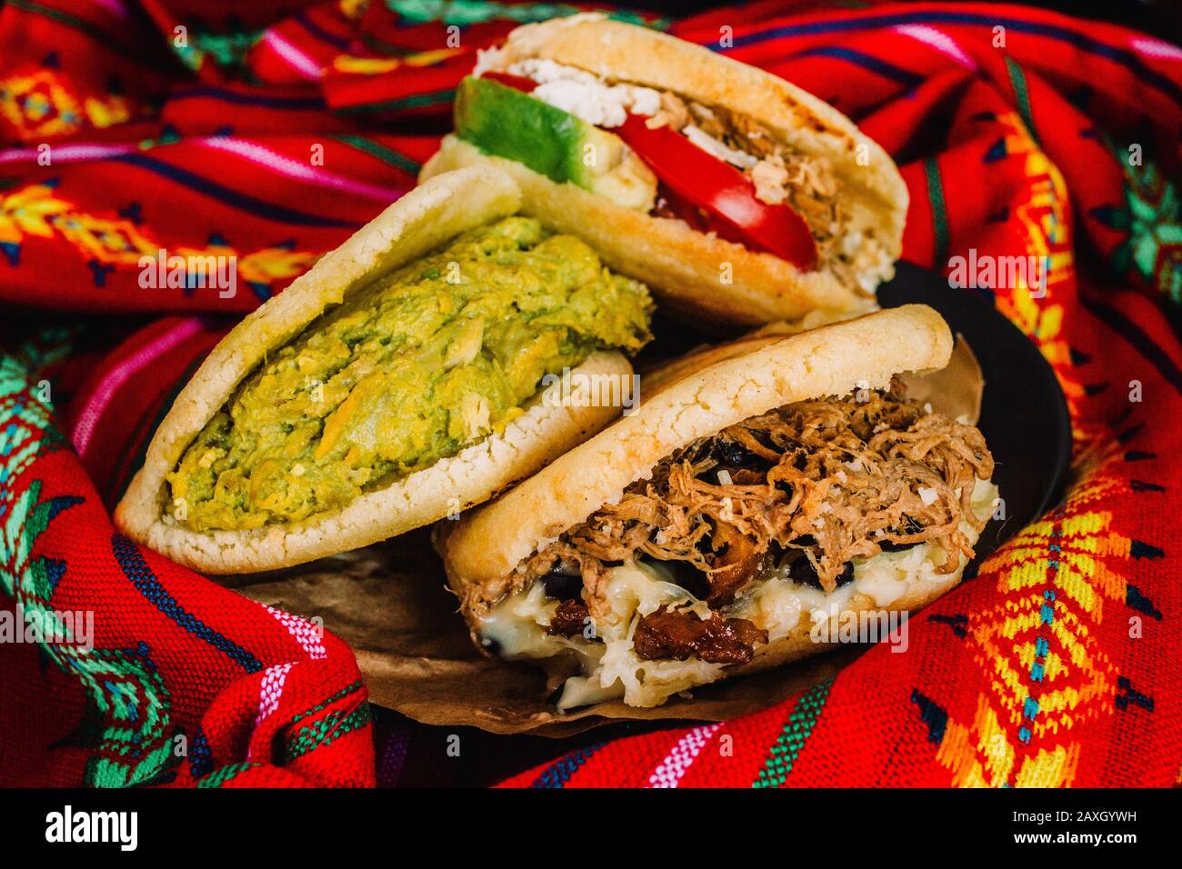 Venezuelan arepas on a colorful background, made with maize and filled with avocado, tomato, meat, cheese and black beans Stock Photo