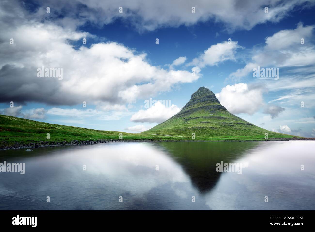 Picturesque landscape with Kirkjufell mountain, clear lake and cloudscape in blue sky Stock Photo
