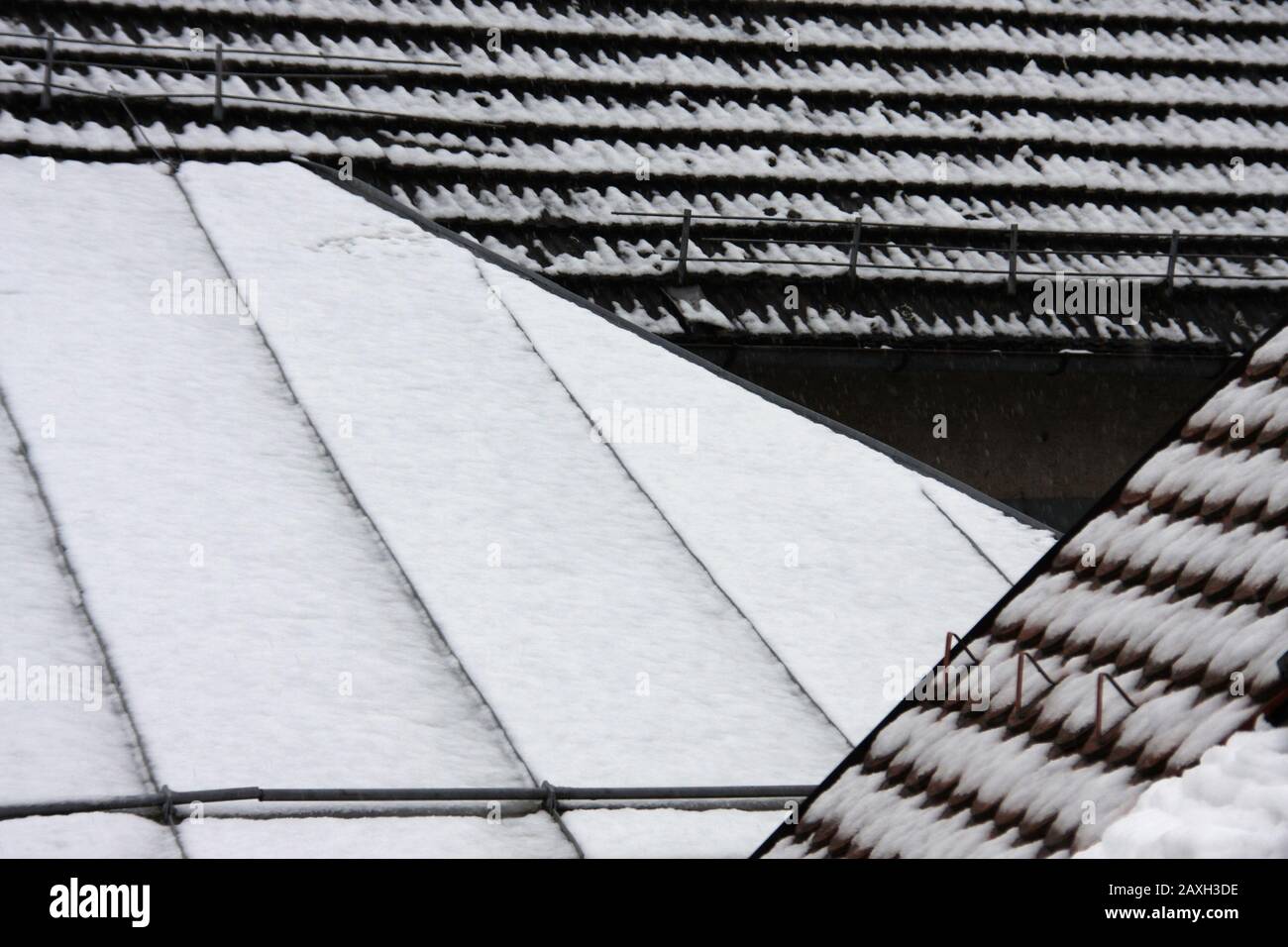 Various snow covered roofs in dew weather close up, wintry mood in february on a cloudy day Stock Photo