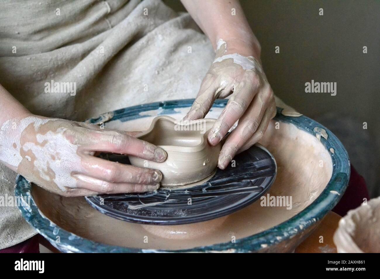 person potter makes clay earthen pot on a potter's wheel in pottery