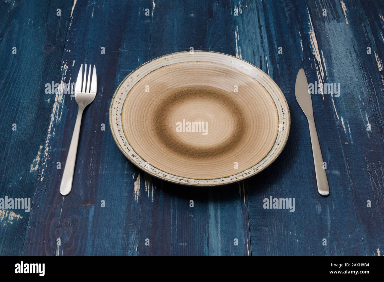 Round Plate with utensils on ocean blue wooden table background side view Stock Photo