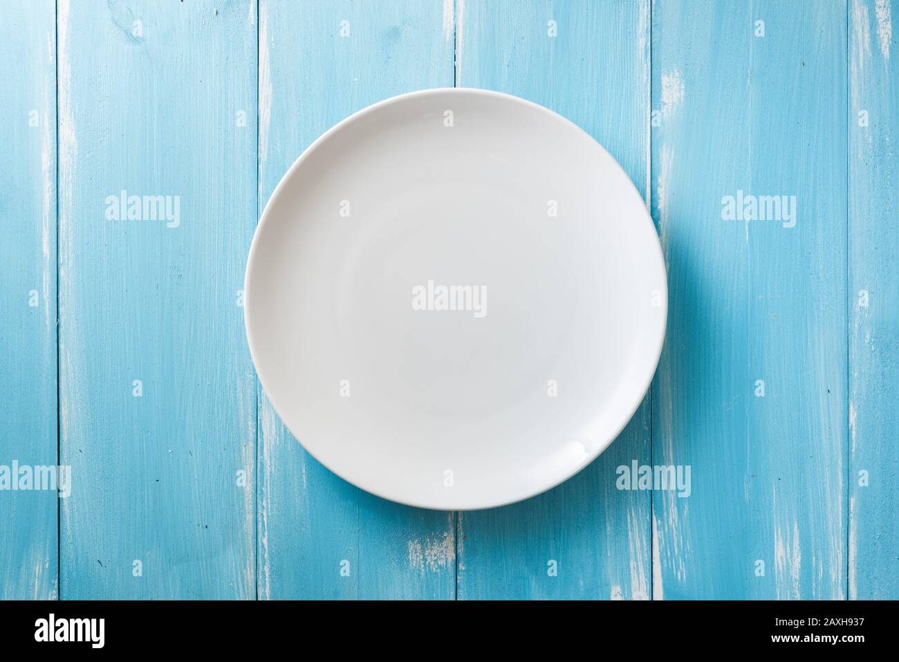 White Round Plate on blue wooden table background Stock Photo