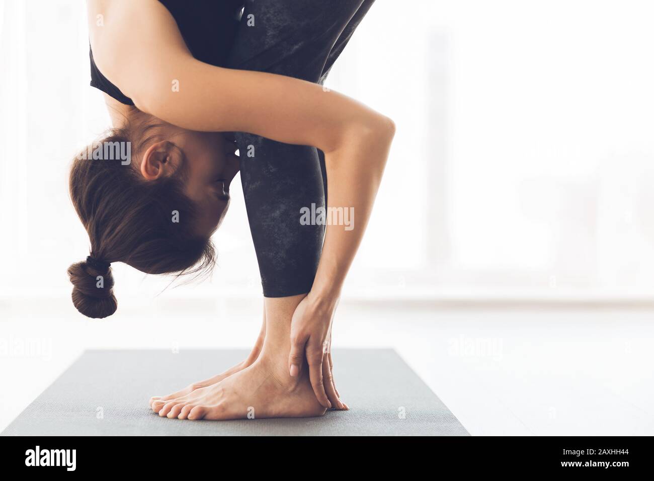 Woman stretching standing in modern light studio Stock Photo