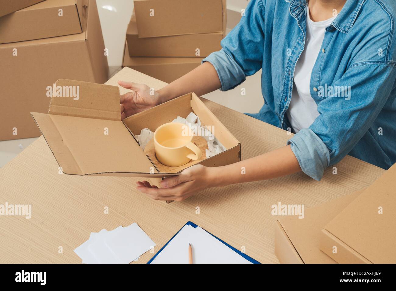 Courier hands packaging parcel at table Stock Photo