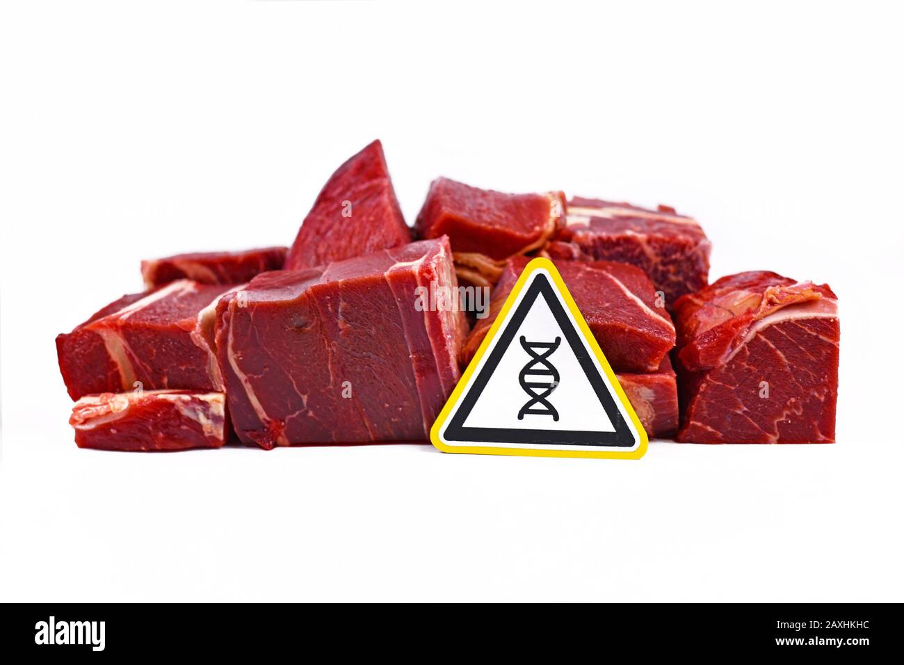Concept for genetically modified meat for human consumption, showing chunks of red meat with yellow DNA gene warning sign Stock Photo
